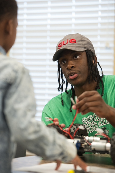 SIUE Noyce intern Gaige Crowell teaches a young student from Alton how to build a rover during the STEM Meets Humanities Robotics Program.